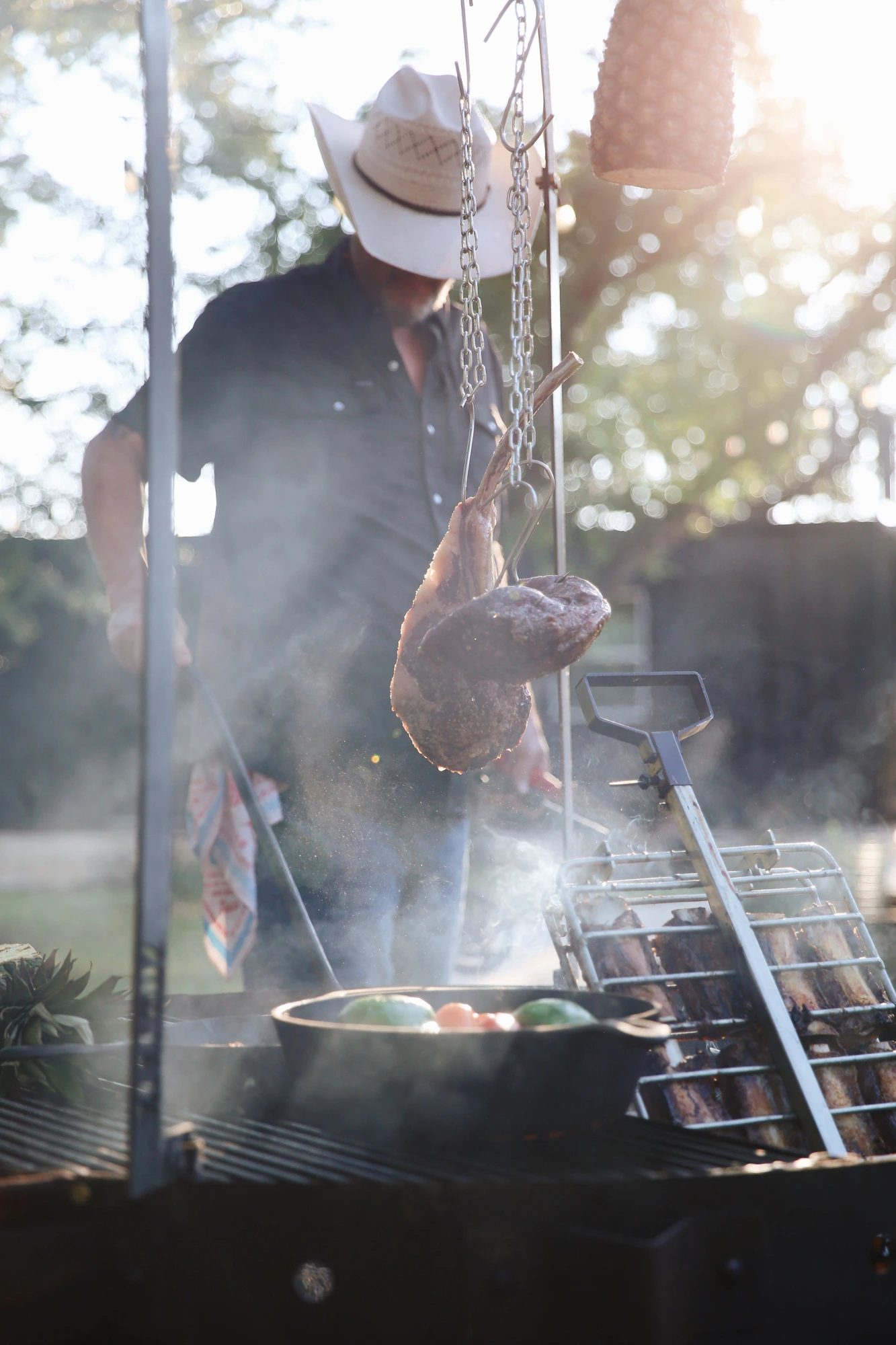 Cast iron skillet of fire-roasted short ribs, carrots, and corn relish over glowing coals